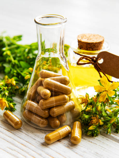 St. John's wort, herbal medical pills in test tube, bottles with natural oil on a table